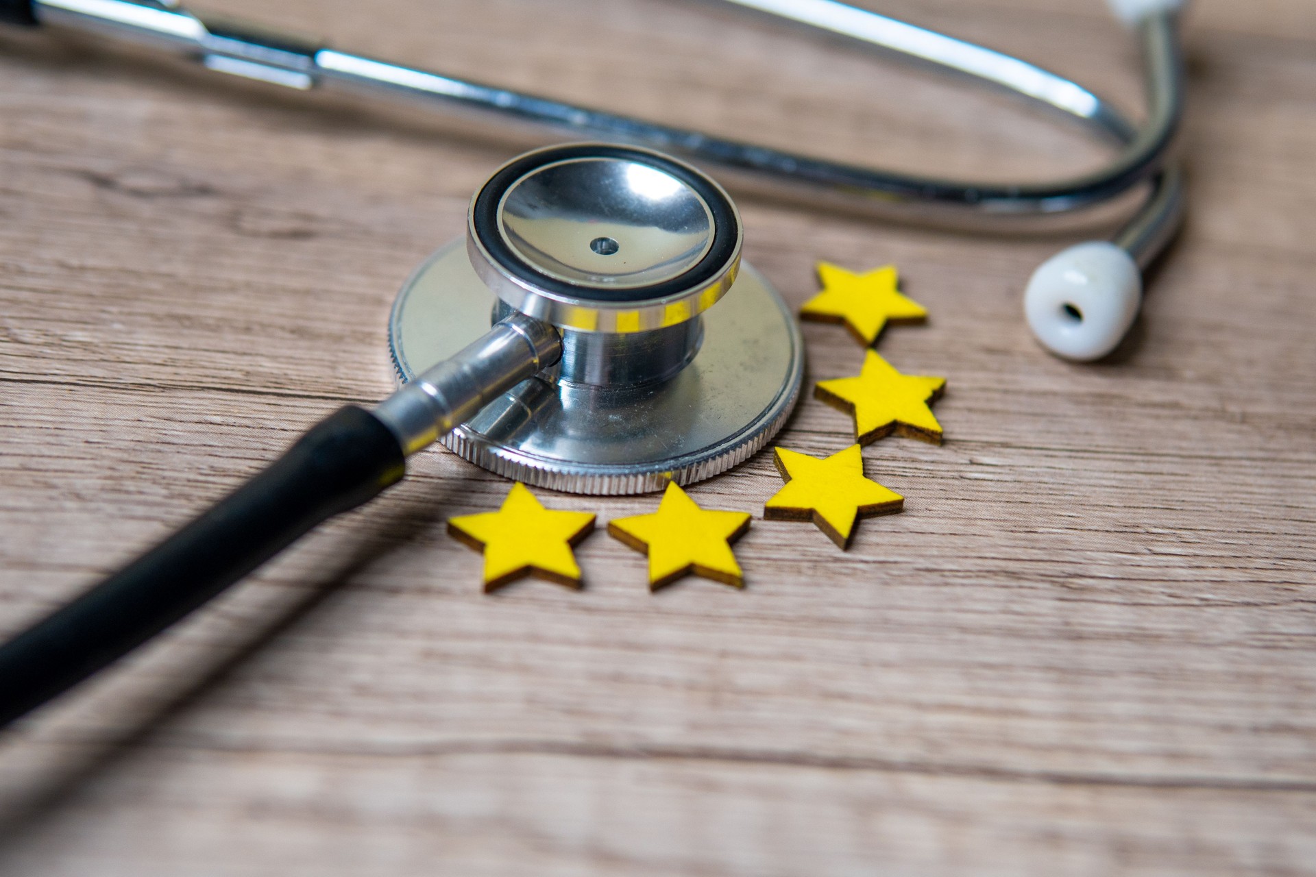 Closeup image of stethoscope and five stars on wooden table with copy space.