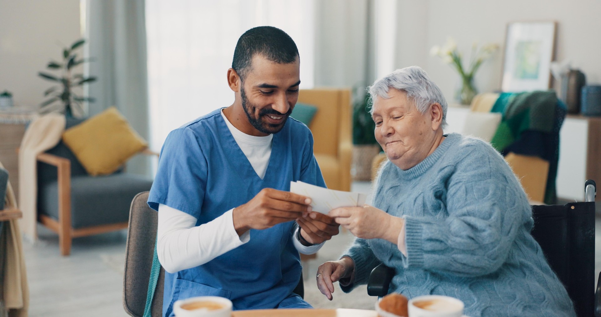 Nursing home, photo album and caregiver with old woman in retirement, break and bonding together. Love, memory or senior person with pictures for support or nostalgia with care, nurse or conversation